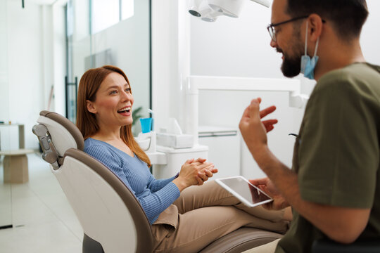 Dentist consulting with a smiling female patient in a modern clinic, discussing treatment options and providing advice, building trust and promoting oral health