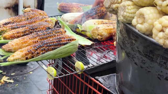 Delicious Mexican elotes grilling over hot coals at traditional street food stall