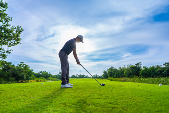 Professional young male golfer swings his club on scenic golf course. 