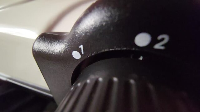 Macro static shot of a black numbered dial selector with textured grip showing levels 1, 2, and 3 on a white medical or home appliance panel.