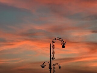 Obraz premium Ornate street lamp silhouette beneath a colorful sunset sky