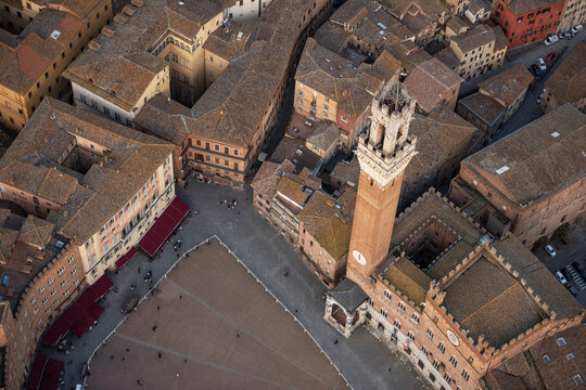 Aerial view of Piazza del Campo and the Torre del Mangia surrounded by historic brick buildings and the shell-shaped square, Siena, Tuscany, Italy.