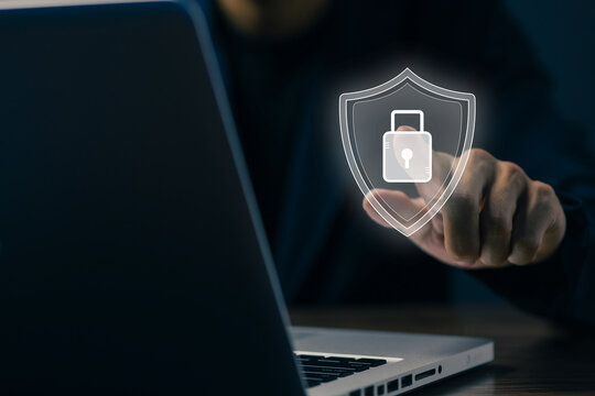 Business professional touching a virtual shield and padlock icon beside a laptop, representing cybersecurity, data protection, privacy, secure access, and digital network defense system.