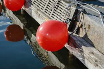 Wooden dock with mooring buoys reflected in calm harbor water © Vladimir Arndt