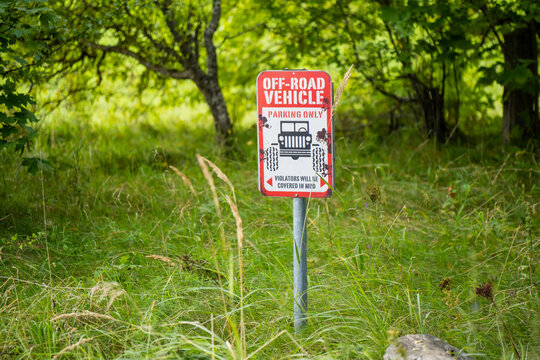 Novelty off road vehicle parking sign mounted on a post among trees and grass, illustrating humorous parking designation for recreational motoring spaces