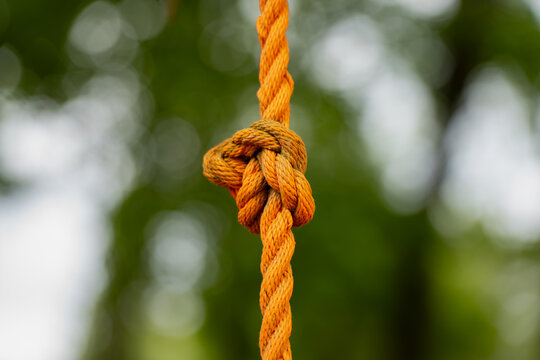 Knotted rope with clearly visible twisted fibers on a suspended length, representing practical cordage connections and the inspection of rope based equipment