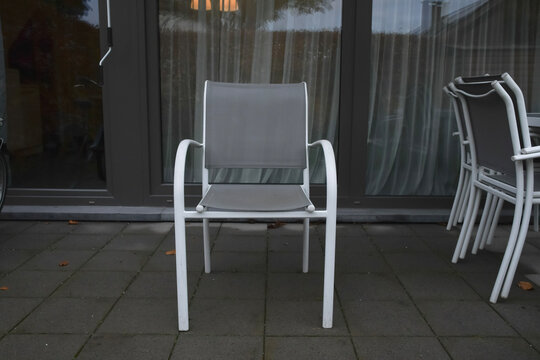 Outdoor patio chair placed on a stone surface in a quiet residential area during the evening