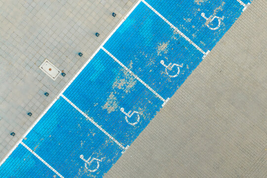 Aerial view of blue handicap parking spaces with white wheelchair symbols painted on paved ground Poland.