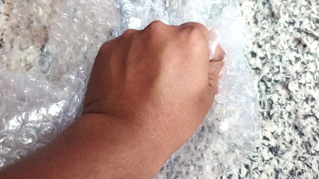 Close up of hands popping plastic bubble wrap packaging material