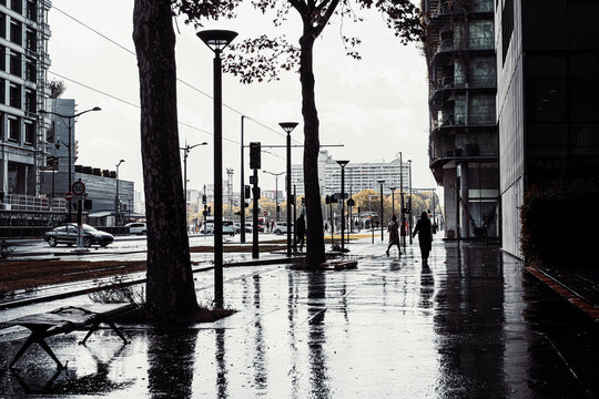 Wet residential street with pedestrians and reflections after rain among urban architecture in Paris France with pedestrians on the wet street