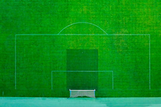 Aerial view of a modern football field with white pitch markings and a goal net on lush green grass in Poland.