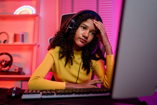 African American teenage girl playing online video game on her computer.
