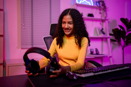 African American girl wearing headphones while playing online video game. 