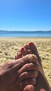 Feet of a couple on the beach sand; relationship and vacation or travel concept