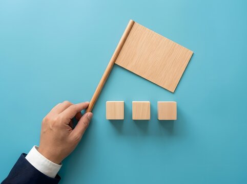 Hand holding wooden flag and blocks on blue background