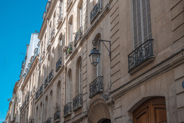 Fototapeta premium Paris haussmann building facade with street lamp and ornate iron balconies against blue sky