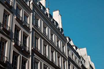 Obraz premium Haussmann architecture in paris featuring classic building facades, many windows, and dormer roofs against a clear blue sky