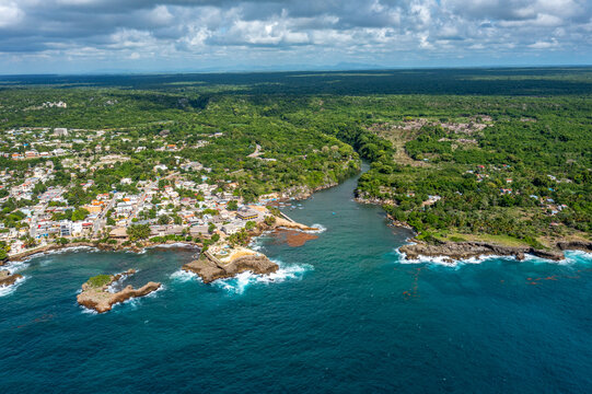 Aerial view of the coastal town of Boca de Yuma, featuring the river mouth meeting the Caribbean Sea, surrounded by lush vegetation in Boca de Yuma, La Altagracia Province, Dominican Republic.