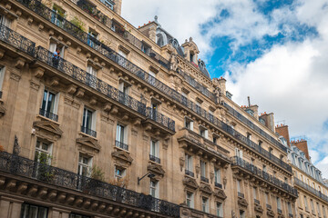 Obraz premium Haussmann style building facade with ornate wrought iron balconies and blue sky in paris, france