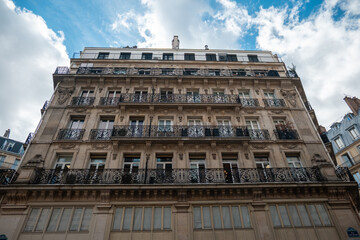Obraz premium Haussmann building facade in paris, france, featuring ornate balconies, windows, and traditional architecture under a cloudy sky