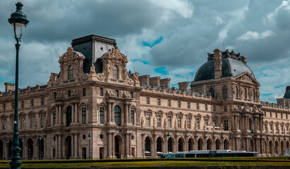 Obraz premium Louvre museum architecture in paris, france, showing historic palace facade, ornate details, and cloudy sky