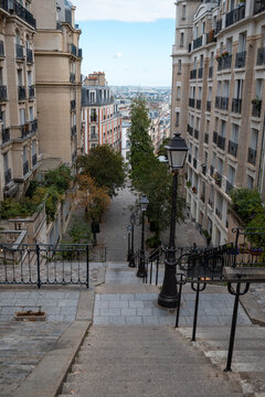 Montmartre street stairs leading down a charming parisian neighborhood with haussmann buildings and city skyline view