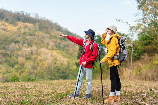 Two hikers with backpacks walking together on a trail in the mountains. 