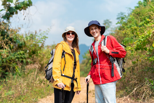 Portrait of Caucasian hikers with backpacks standing on a trail in mountains.