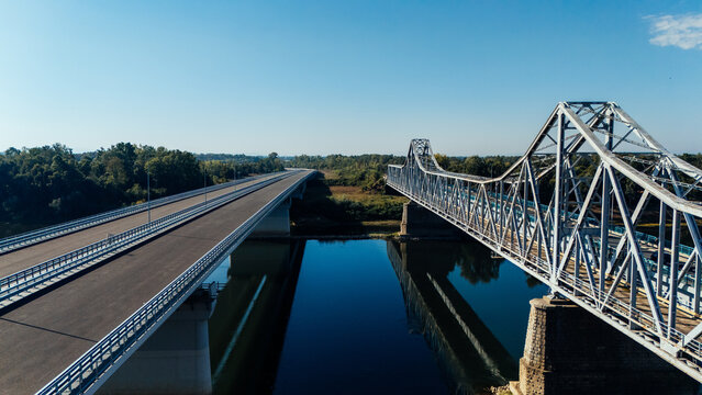 Aerial view of the Racha Bridge and the adjacent modern highway bridge spanning the Sava River, surrounded by lush greenery in Sremska Raca, Vojvodina, Serbia.