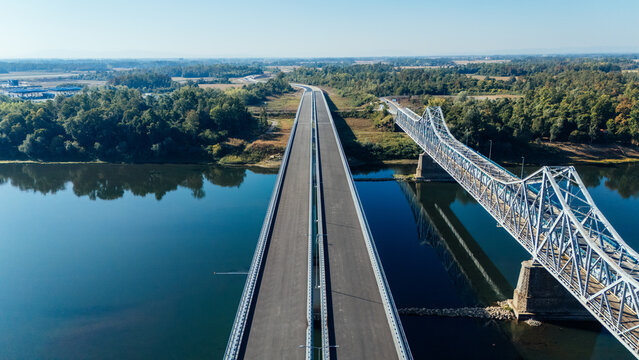 Aerial view of the Racha Bridge spanning the Sava River with a modern highway bridge alongside, surrounded by lush green forests in Sremska Raca, Vojvodina, Serbia.