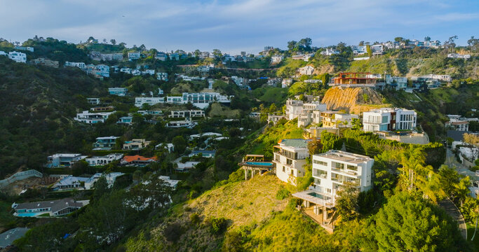 Aerial view of luxury hillside homes and modern mansions nestled in the lush green hills of Los Angeles, California, United States.