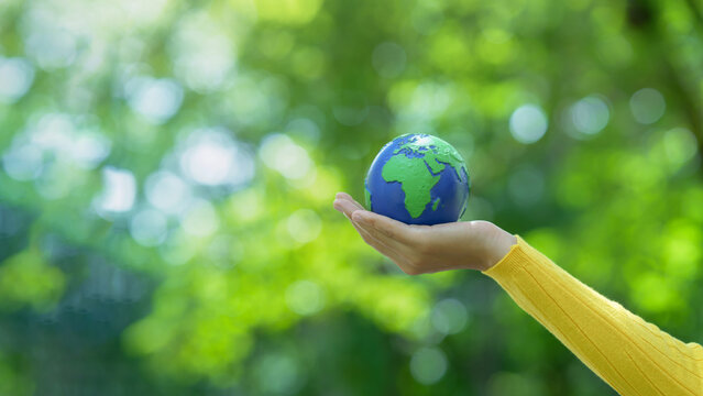 Hand holding small earth globe promoting environmental conservation, sustainability, ecology, global warming awareness and nature protection. World Environment Day. ESG, co2, CSR and net zero.