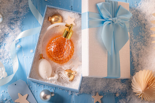 Wonderful perfume rests right beside festive Christmas decorations on table.
