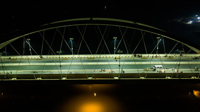 Aerial view of the illuminated bridge over the river at night with street lights and vehicles in Narail, Khulna Division, Bangladesh.