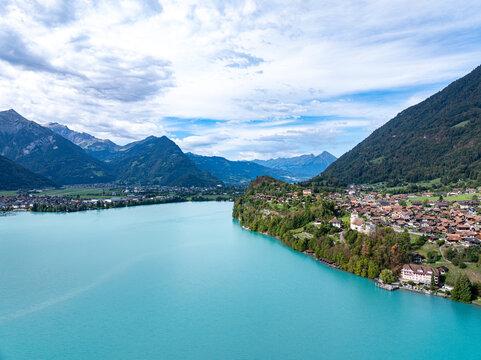 Aerial view of Ringgenberg Castle and Ruin overlooking the turquoise waters of Lake Brienz with the historic village and surrounding mountains in Ringgenberg, Canton of Bern, Switzerland.