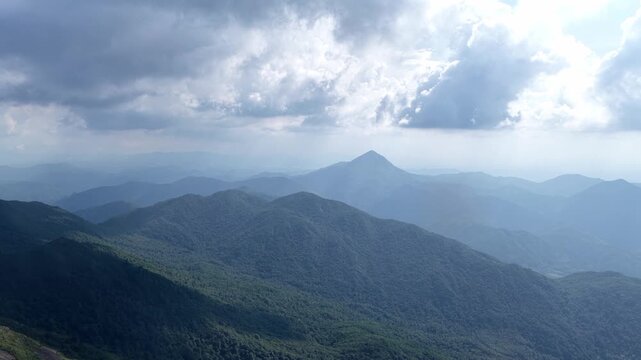 Layered green mountain ranges under cloudy sky