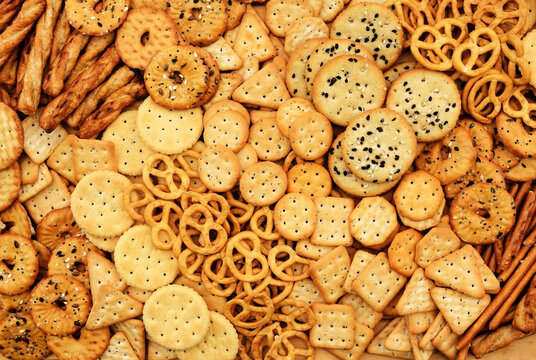 Colorful mix of salty crackers varieties: sticks. pretzels and round with seeds. Snacks food background
