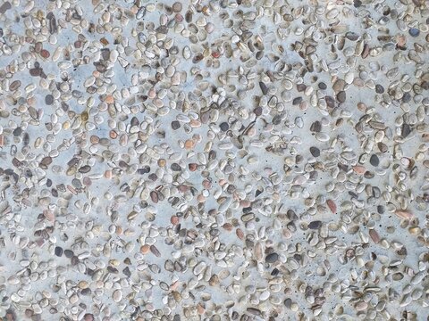 Close up image of grey pebbles embedded in rough concrete create a decorative stone floor pattern suitable for interior design projects and backgrounds.