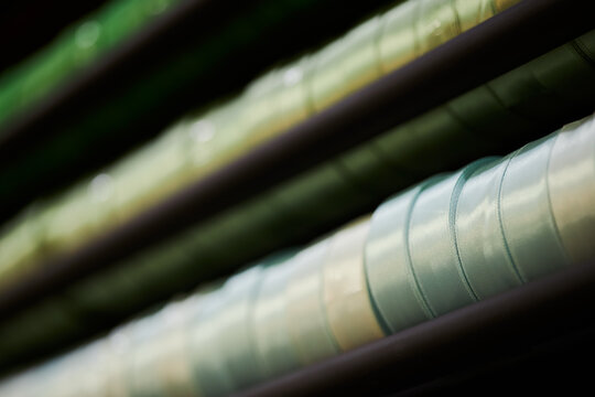 Close up shot of colorful ribbon spools organized on shelf in sewing workshop. Suitable for craft store advertising, textile industry marketing, and hobby supplies