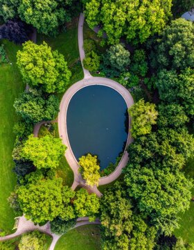 Aerial view of a serene park with a central pond surrounded by lush trees and winding paths.