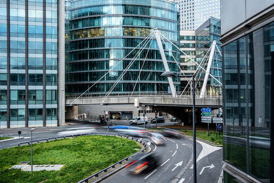 Curved glass office buildings with traffic on an urban road in La Defense district of Paris France showing contemporary business architecture