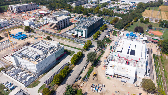 Aerial view of a large data center cluster with modern industrial buildings, solar panels, and construction equipment in Castelletto, Lombardia, Italy.