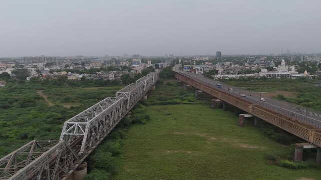 Aerial view of parallel railway and road bridges across green river landscape in Bharuch, Gujarat, India