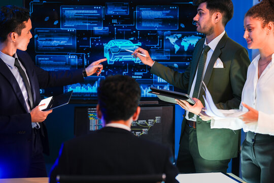 Three engineers cross-reference the documents with the wireframe while one of them turns the pages of the specification inside a dark modern design studio during a late working session