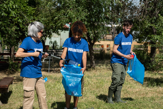 Group of volunteers wearing blue shirts cleaning litter in a park
