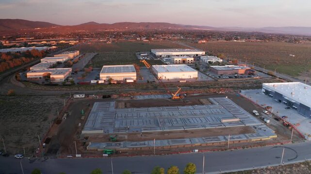 Wide aerial panning shot of a large industrial site under construction at dawn in Palmdale, California. 4K
