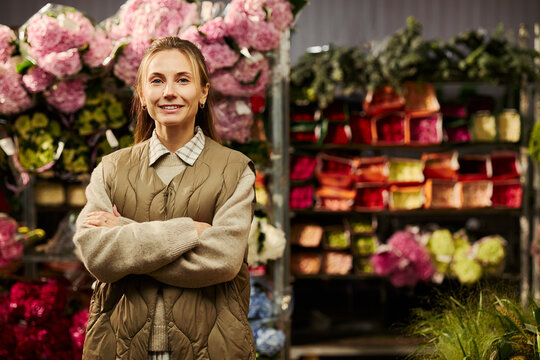 Portrait of smiling young Caucasian female florist standing with arms crossed in flower shop. Small business ownership and retail marketing concept
