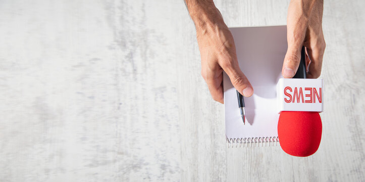 Journalist holding a microphone and notepad.