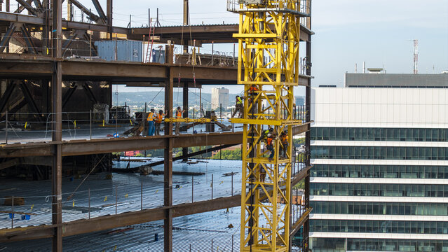 Aerial view of a construction site with a yellow crane and workers on a steel frame in Cambridge, Massachusetts, United States.