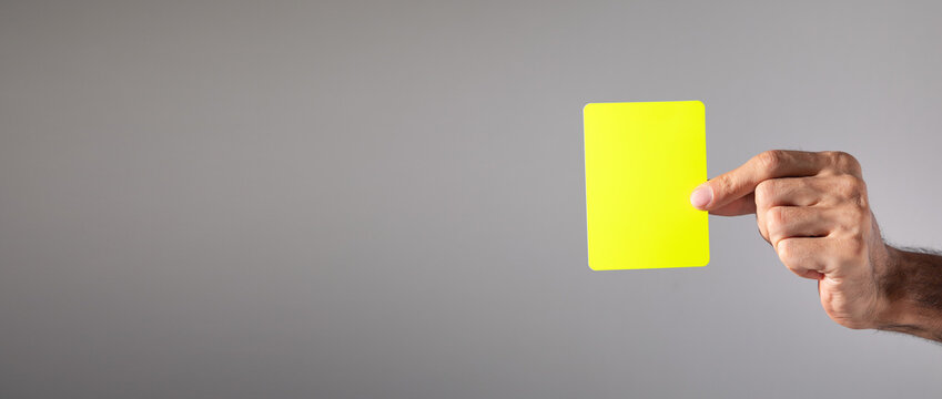 Male hand showing yellow card.